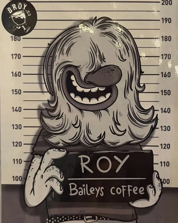 Poster karakter Roy berambut panjang tebal dengan papan bertuliskan Baileys coffee